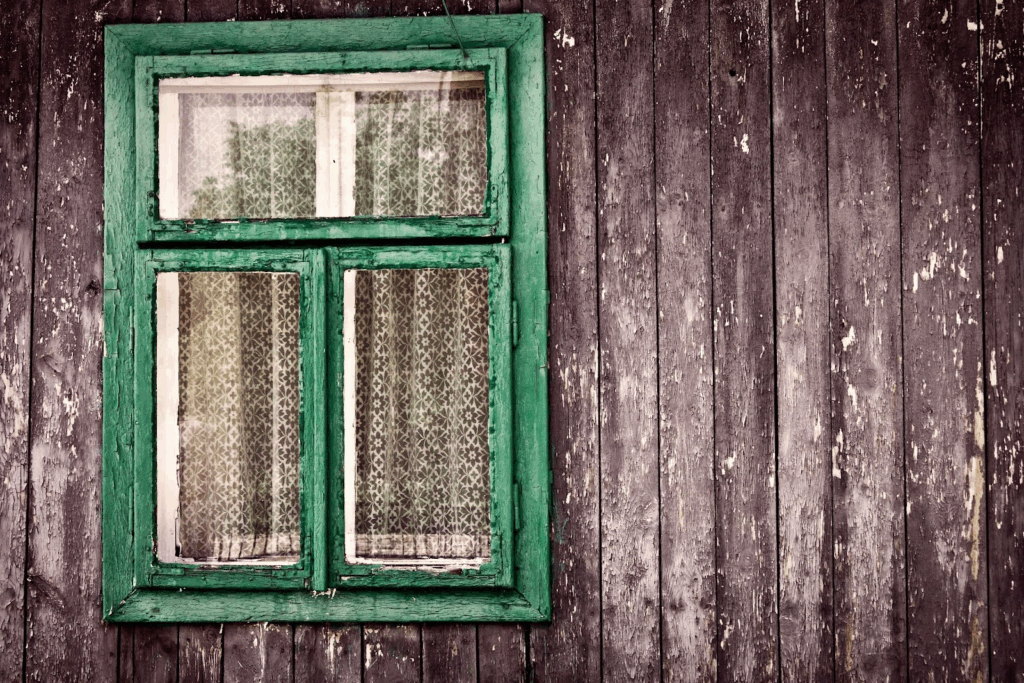 a green wooden window on the side of brown building