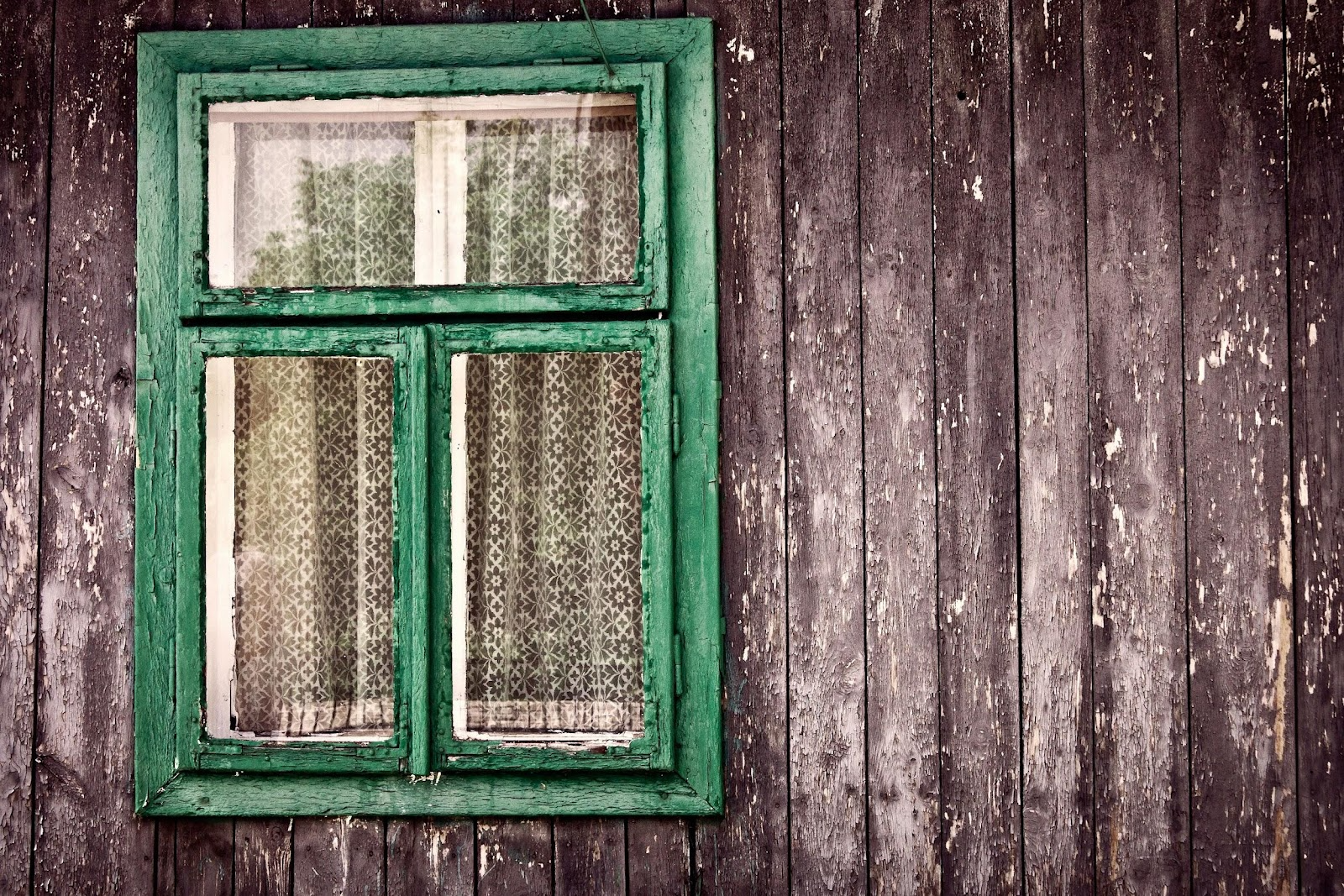 a green wooden window on the side of brown building